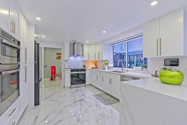 kitchen with wall chimney exhaust hood, marble finish floor, stainless steel appliances, white cabinetry, and a sink