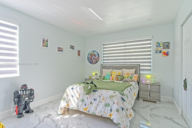 bedroom with marble finish floor, baseboards, and a textured ceiling