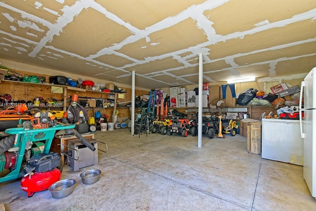 garage featuring a workshop area, fridge, and freestanding refrigerator