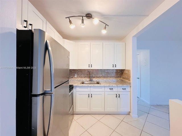 kitchen with a sink, freestanding refrigerator, and white cabinetry