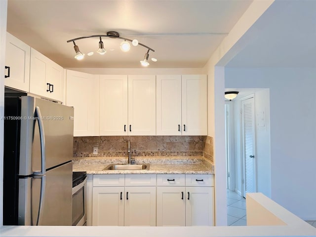 kitchen with stainless steel appliances, white cabinets, a sink, and tasteful backsplash