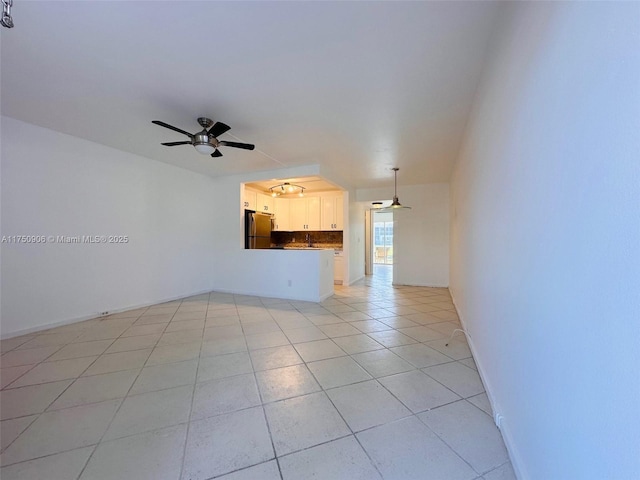 spare room with light tile patterned floors, a ceiling fan, and baseboards