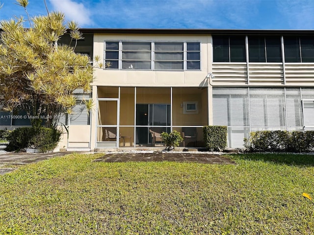 rear view of property with a yard and stucco siding