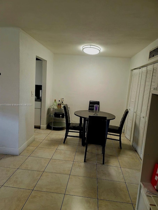 dining space featuring light tile patterned floors, baseboards, and visible vents