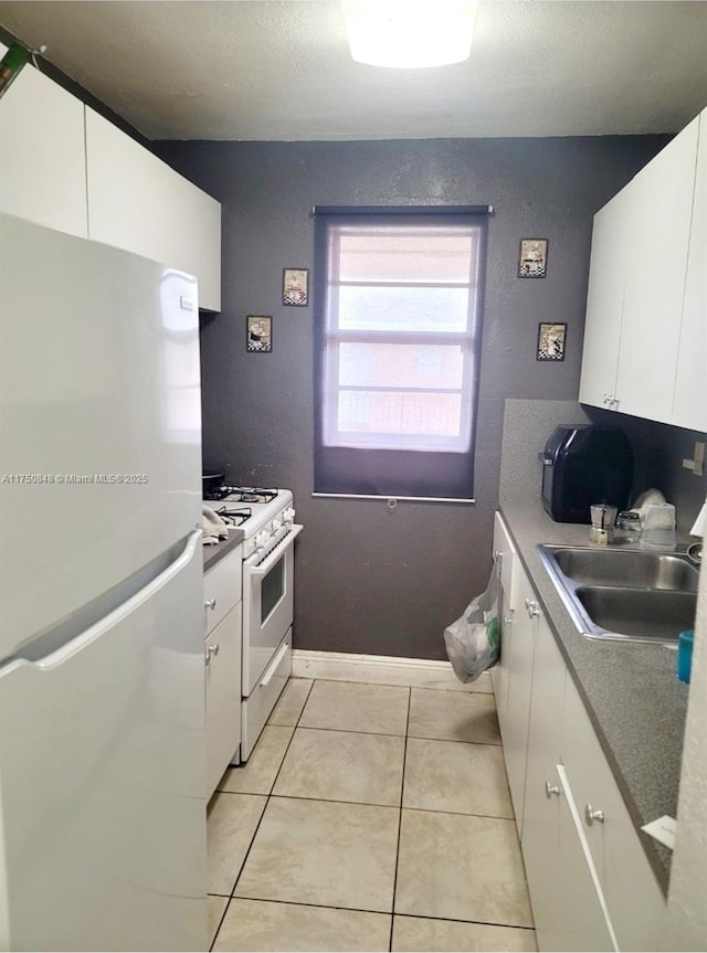 kitchen with light countertops, white appliances, white cabinets, and a sink