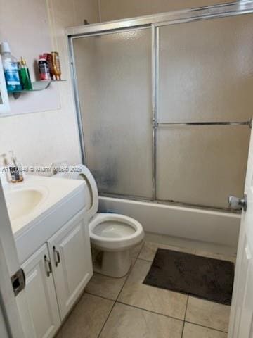 full bathroom with bath / shower combo with glass door, tile patterned flooring, vanity, and toilet