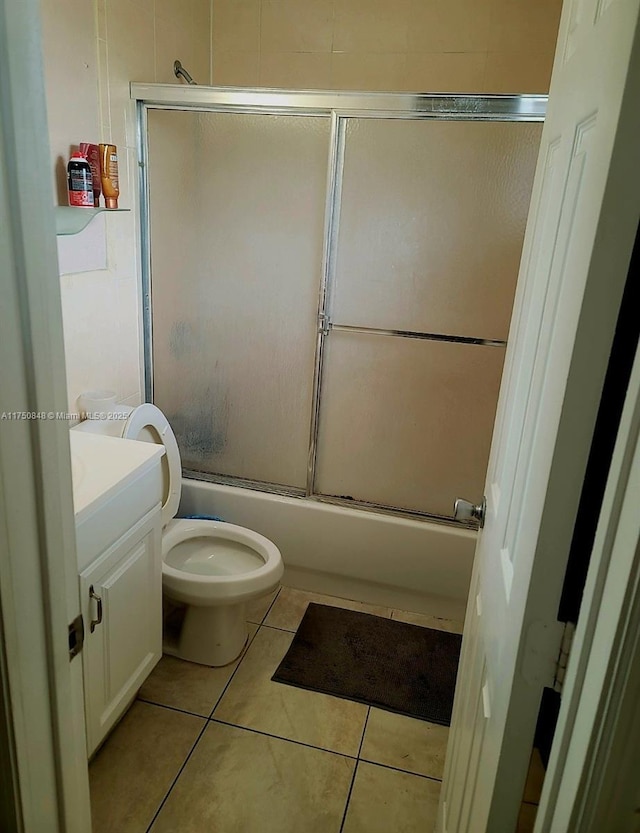 full bath featuring toilet, combined bath / shower with glass door, tile patterned flooring, and vanity