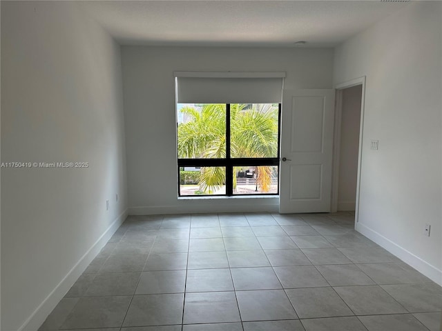 empty room featuring light tile patterned flooring and baseboards