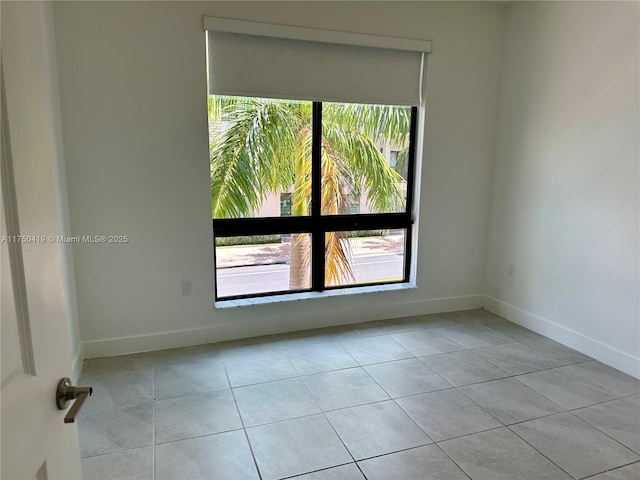 unfurnished room with light tile patterned floors and baseboards