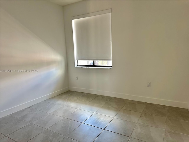 spare room with light tile patterned floors and baseboards