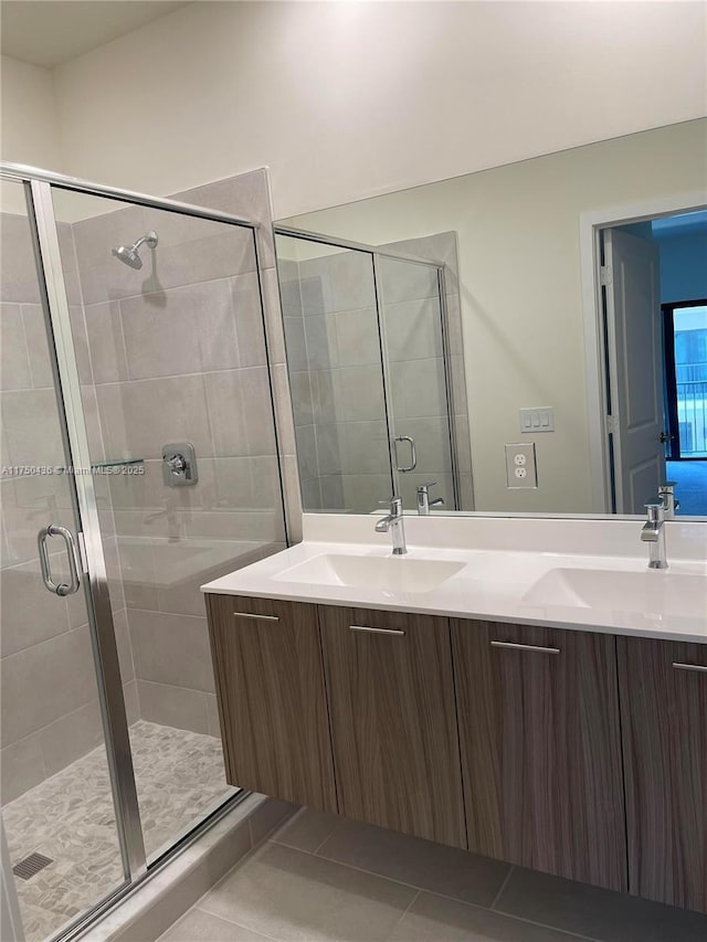 full bath featuring double vanity, a stall shower, a sink, and tile patterned floors