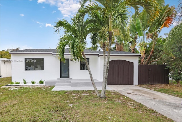 view of front facade featuring a garage, fence, driveway, stucco siding, and a front yard