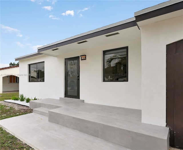 view of exterior entry featuring stucco siding