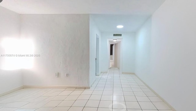 empty room with baseboards, visible vents, and light tile patterned flooring