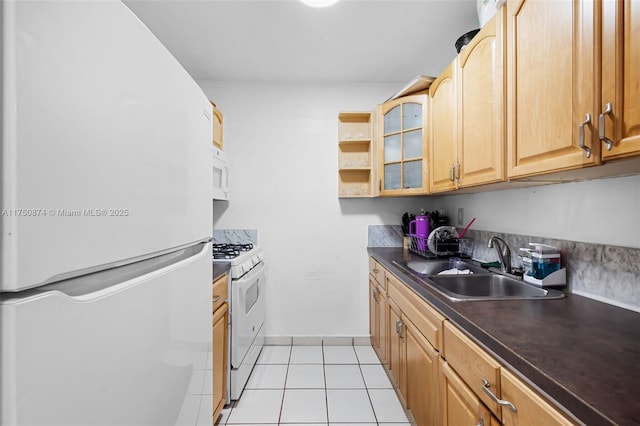 kitchen with dark countertops, glass insert cabinets, light tile patterned flooring, a sink, and white appliances