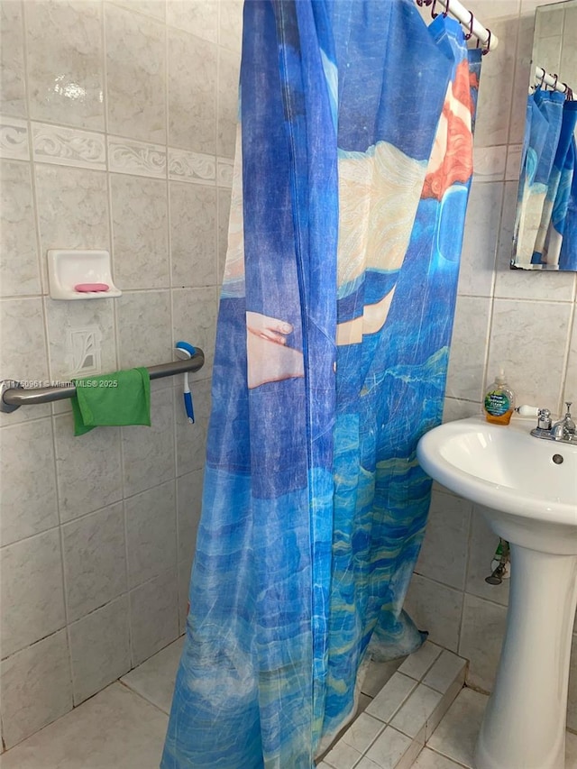 full bathroom featuring a shower with shower curtain, a sink, tile walls, and tile patterned floors