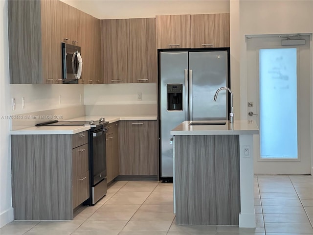 kitchen with brown cabinetry, modern cabinets, appliances with stainless steel finishes, light countertops, and light tile patterned flooring