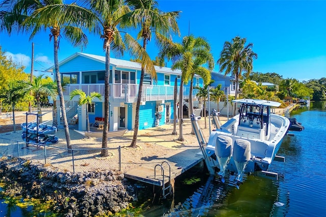 view of play area featuring a dock, a water view, boat lift, and fence