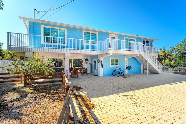 rear view of property featuring an outdoor hangout area, stairway, a patio area, and fence