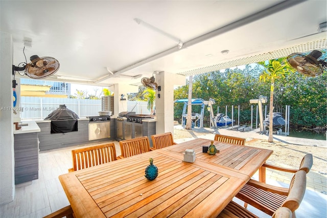 view of patio / terrace featuring exterior kitchen, outdoor dining space, fence, and grilling area