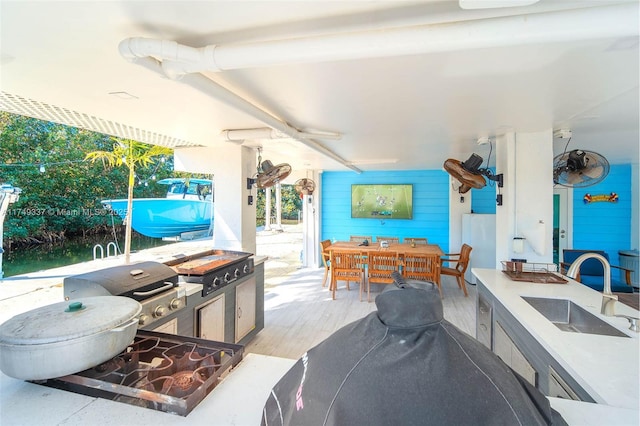 view of patio / terrace featuring exterior kitchen, outdoor dining area, a sink, and area for grilling