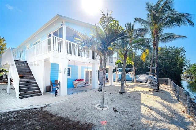 back of property featuring a sunroom, a patio area, fence, and stairway