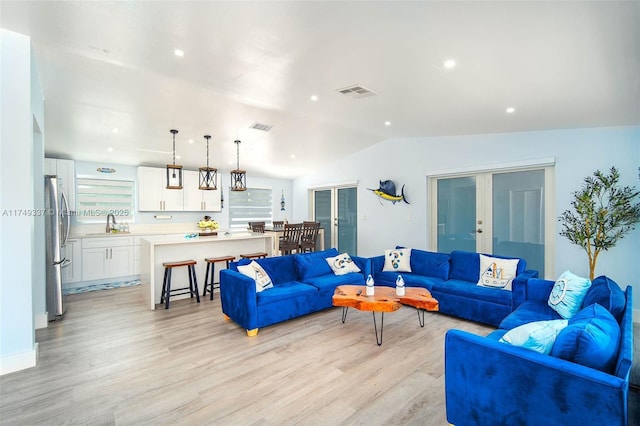 living area with vaulted ceiling, french doors, visible vents, and light wood-style floors