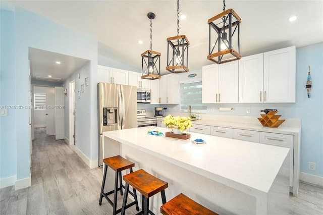 kitchen with light countertops, a kitchen island, white cabinetry, and stainless steel appliances