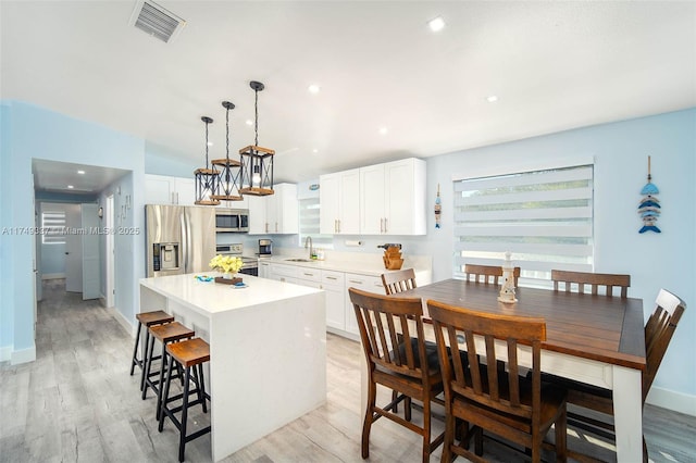 kitchen featuring a sink, visible vents, light countertops, appliances with stainless steel finishes, and decorative light fixtures