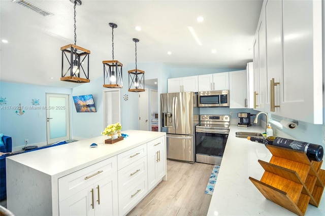 kitchen with stainless steel appliances, a center island, white cabinets, and hanging light fixtures