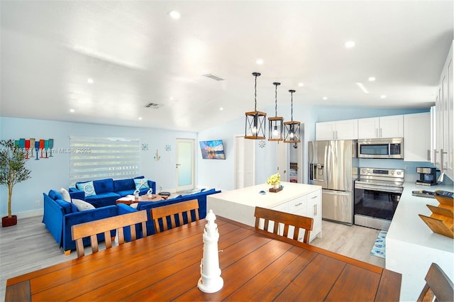 dining area with lofted ceiling, light wood finished floors, and visible vents