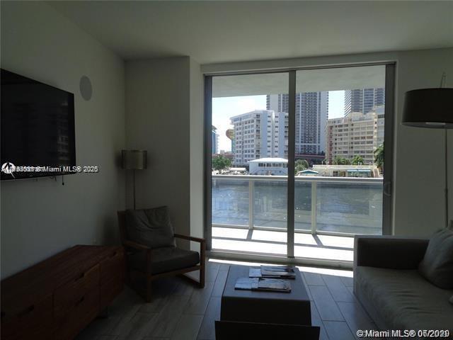 living area with a view of city, floor to ceiling windows, and wood finished floors