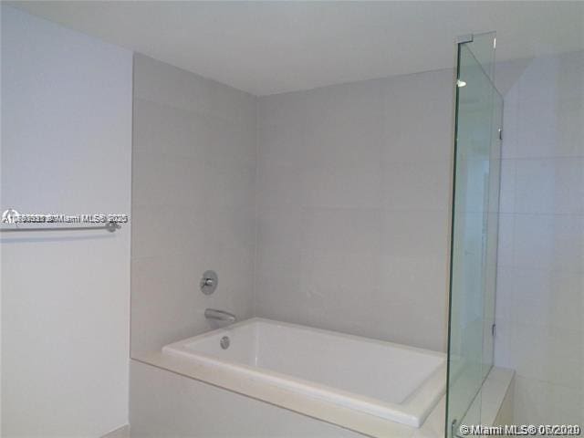 full bath with a washtub and a tile shower