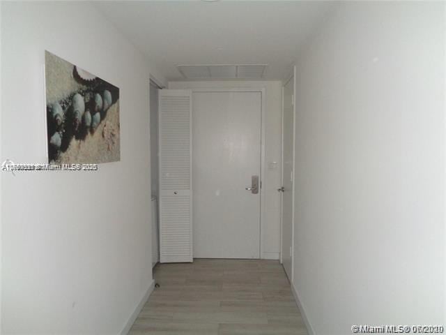 hallway with light wood-type flooring, visible vents, and baseboards