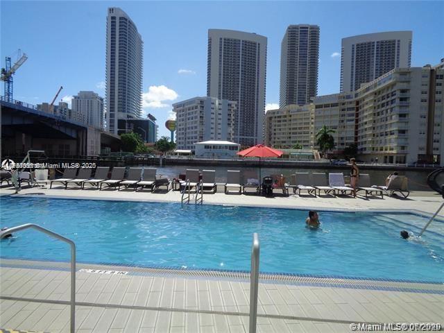 pool featuring a view of the beach, a city view, a patio, and a water view