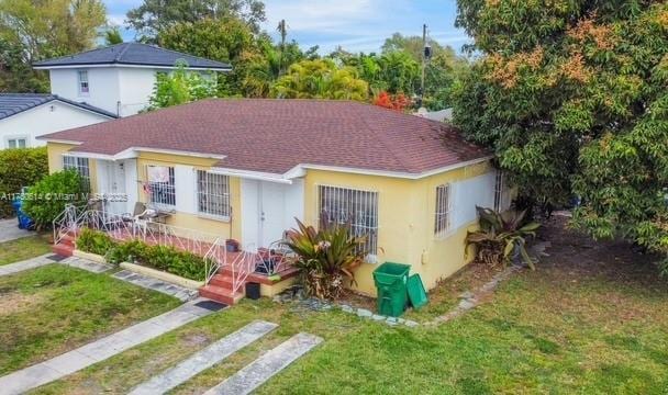 2655 SW 34th Ct, Miami, FL 33133 - view of front facade with roof with shingles, a front yard, and stucco siding