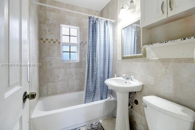 bathroom with toilet, tile walls, and shower / bathtub combination with curtain