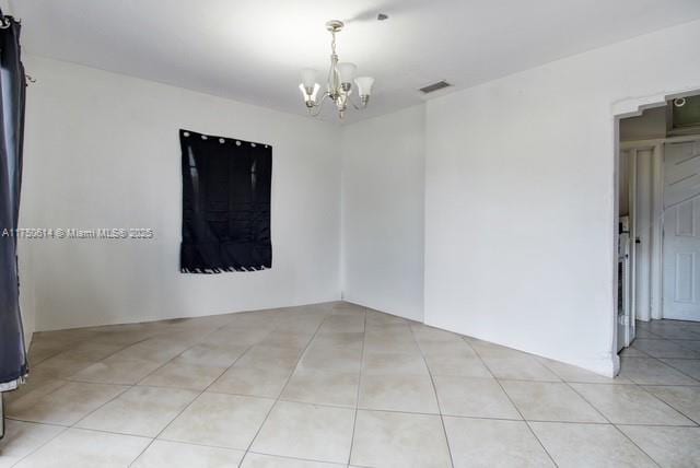 unfurnished room featuring light tile patterned floors, visible vents, and a notable chandelier