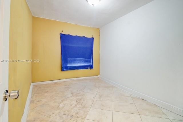 empty room with tile patterned flooring and baseboards