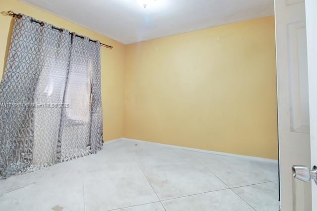 tiled empty room featuring baseboards