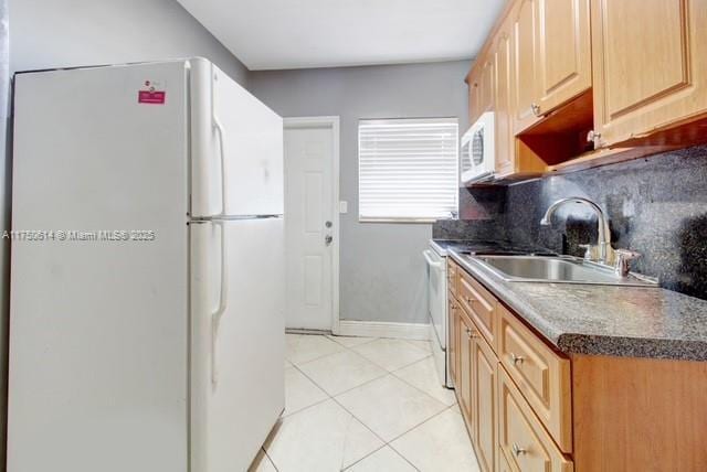 kitchen with white appliances, light tile patterned floors, decorative backsplash, light brown cabinetry, and a sink