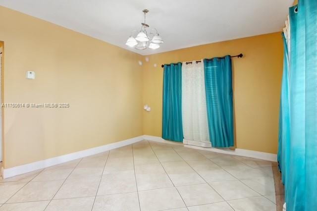 empty room featuring a chandelier, tile patterned flooring, and baseboards