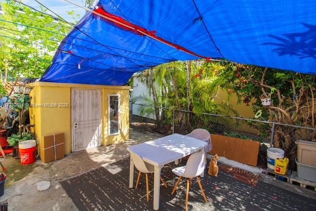 view of patio with an outbuilding, outdoor dining area, and fence