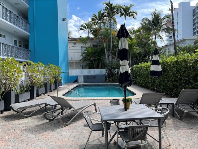 community pool with a patio area and fence