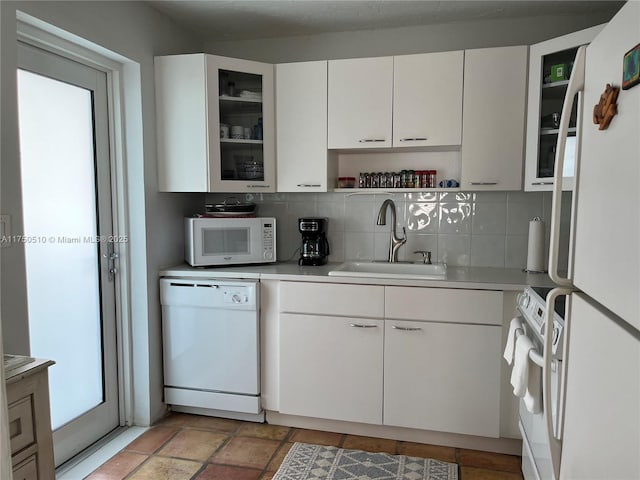 kitchen with white appliances, light countertops, a sink, and decorative backsplash