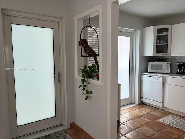 kitchen featuring light countertops, glass insert cabinets, white cabinets, white appliances, and baseboards