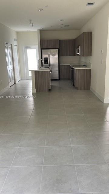 kitchen with light tile patterned floors, modern cabinets, open floor plan, stainless steel appliances, and light countertops