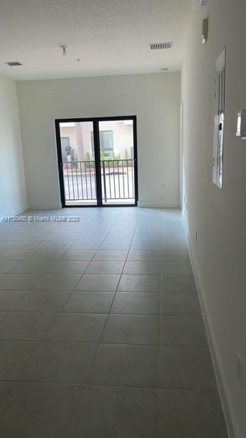 tiled empty room with visible vents and baseboards