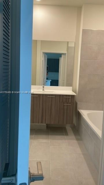 bathroom with a tub to relax in, tile patterned flooring, and vanity