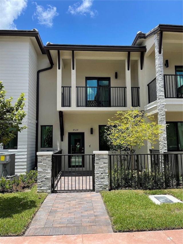 townhome / multi-family property featuring a fenced front yard, a gate, and stucco siding